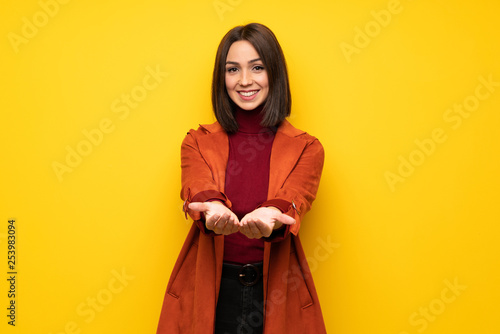 Young woman with coat holding copyspace imaginary on the palm to insert an ad © luismolinero