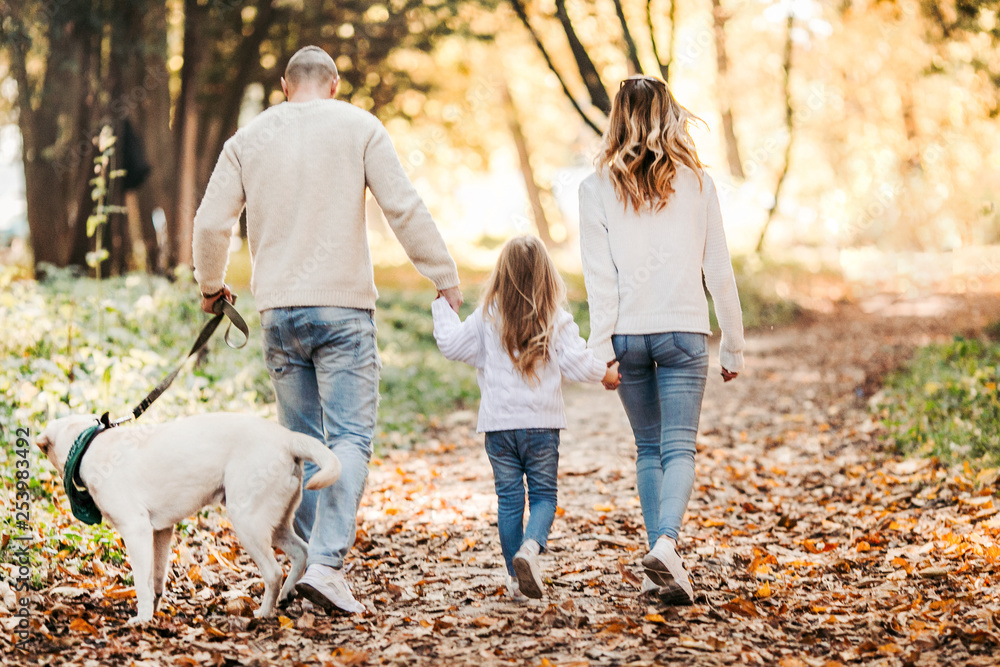 Fototapeta premium Happy beautiful family with dog labrador is having fun together walking the in park.