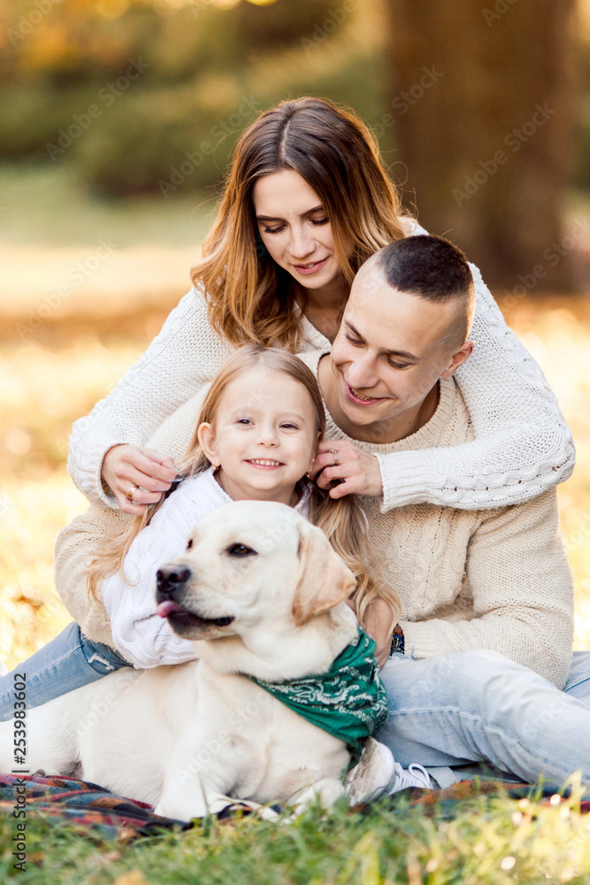 Happy beautiful family with dog labrador is having fun are sitting on green grass in park. Happy beautiful family with dog labrador is having fun are sitting on green grass in park.