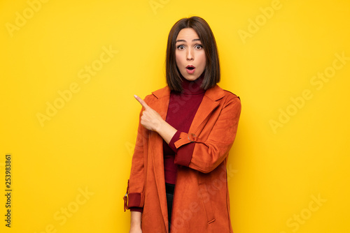 Young woman with coat surprised and pointing side © luismolinero
