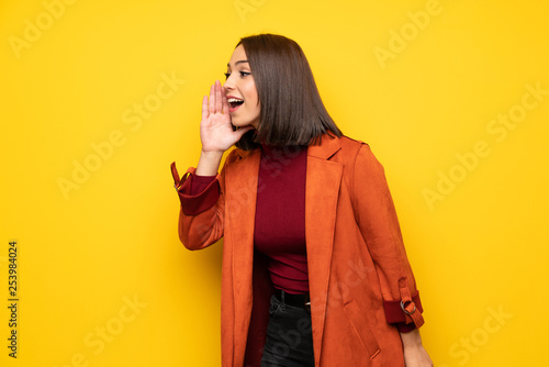 Young woman with coat shouting with mouth wide open to the lateral © luismolinero