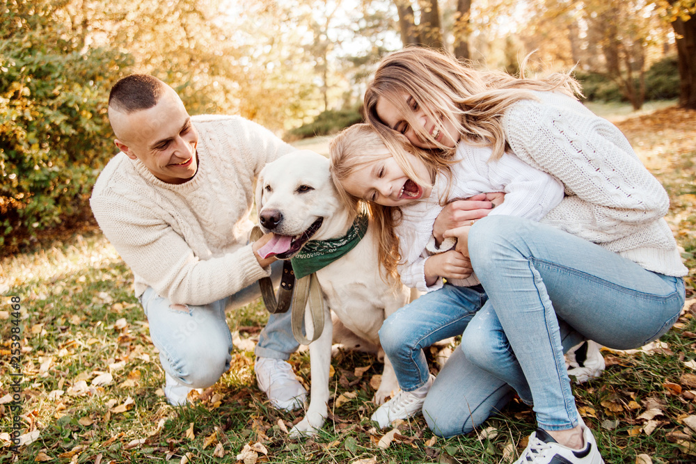 Happy beautiful family with dog labrador is having fun are sitting on green grass in park. Happy beautiful family with dog labrador is having fun are sitting on green grass in park.