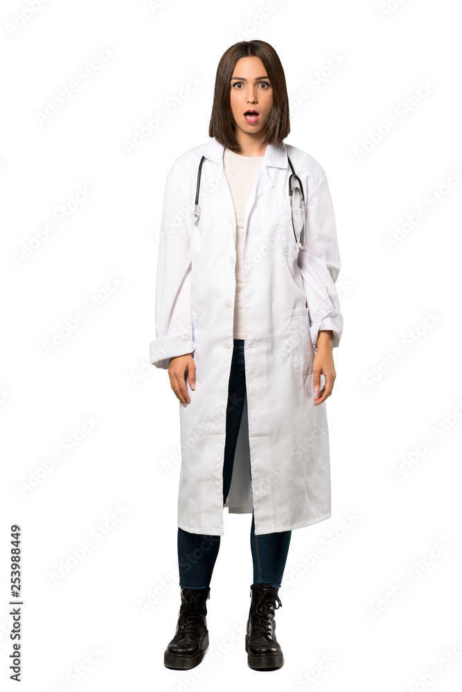 A full-length shot of a Young doctor woman surprised and shocked while looking right over isolated white background A full-length shot of a Young doctor woman surprised and shocked while looking right over isolated white background