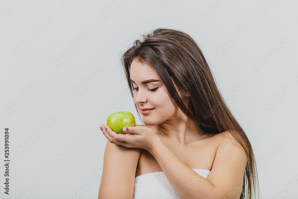 Beautiful young girl with a natural natural make-up and perfect skin with apple in her hand. Beauty face Picture taken in the studio on a white background. Beautiful young girl with a natural natural make-up and perfect skin with apple in her hand. Beauty face Picture taken in the studio on a white background.