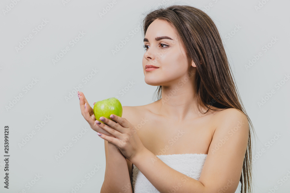 Portrait of an attractive Caucasian girl smiles. Woman isolated on white background. Holds the green apple in hand. Good clean skin. Portrait of an attractive Caucasian girl smiles. Woman isolated on white background. Holds the green apple in hand. Good clean skin.