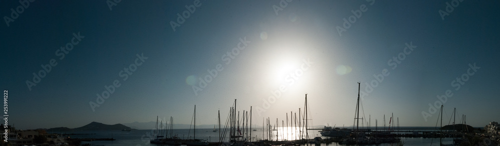 Sail boats in the ocean, the blue sky and the sun in the background - back light