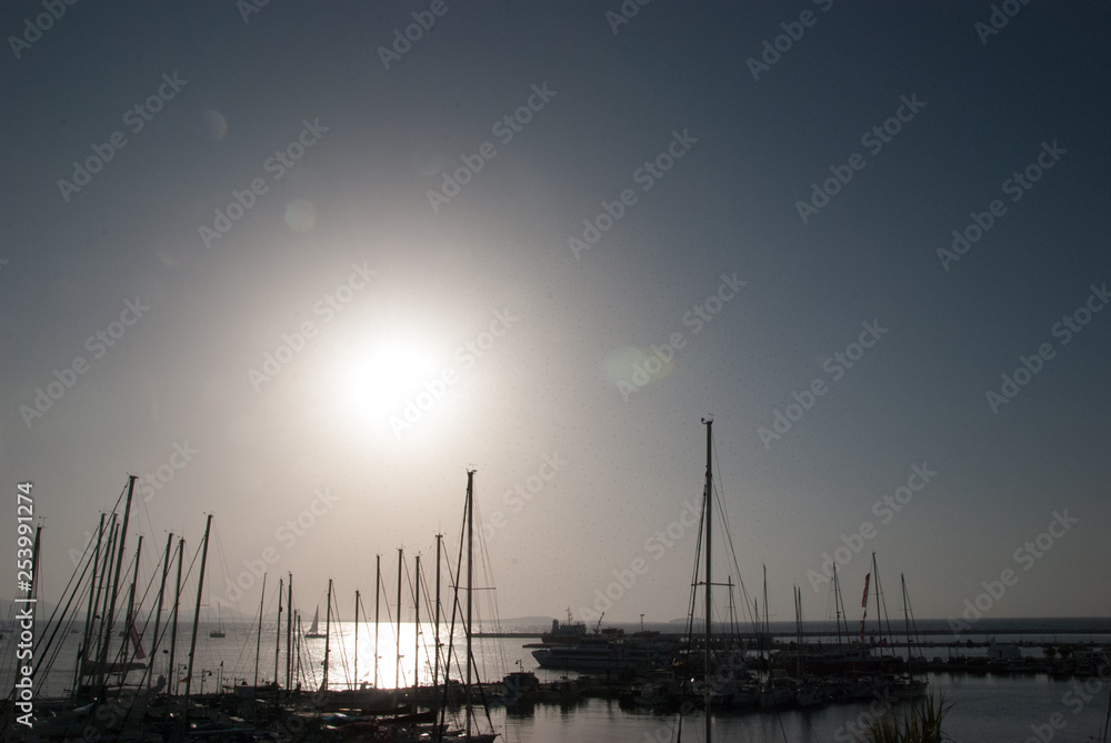 Sail boats in the ocean, the blue sky and the sun in the background - back light