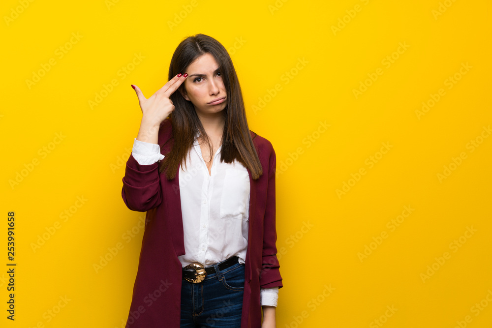 Young woman over yellow wall with problems making suicide gesture Young woman over yellow wall with problems making suicide gesture