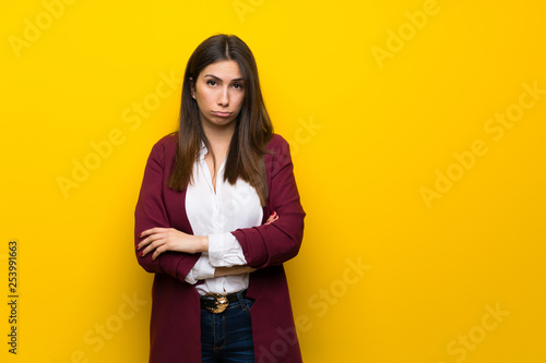 Young woman over yellow wall with sad and depressed expression © luismolinero