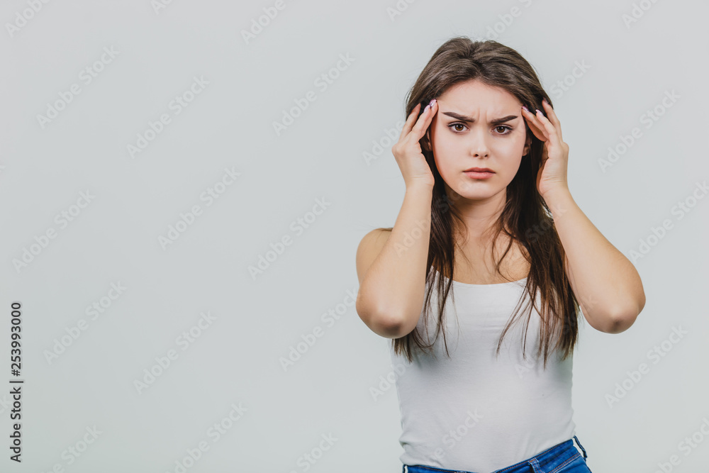 A young beautiful girl stands on a gray background while dressed in blue jeans and a white T-shirt. A young beautiful girl stands on a gray background while dressed in blue jeans and a white T-shirt.