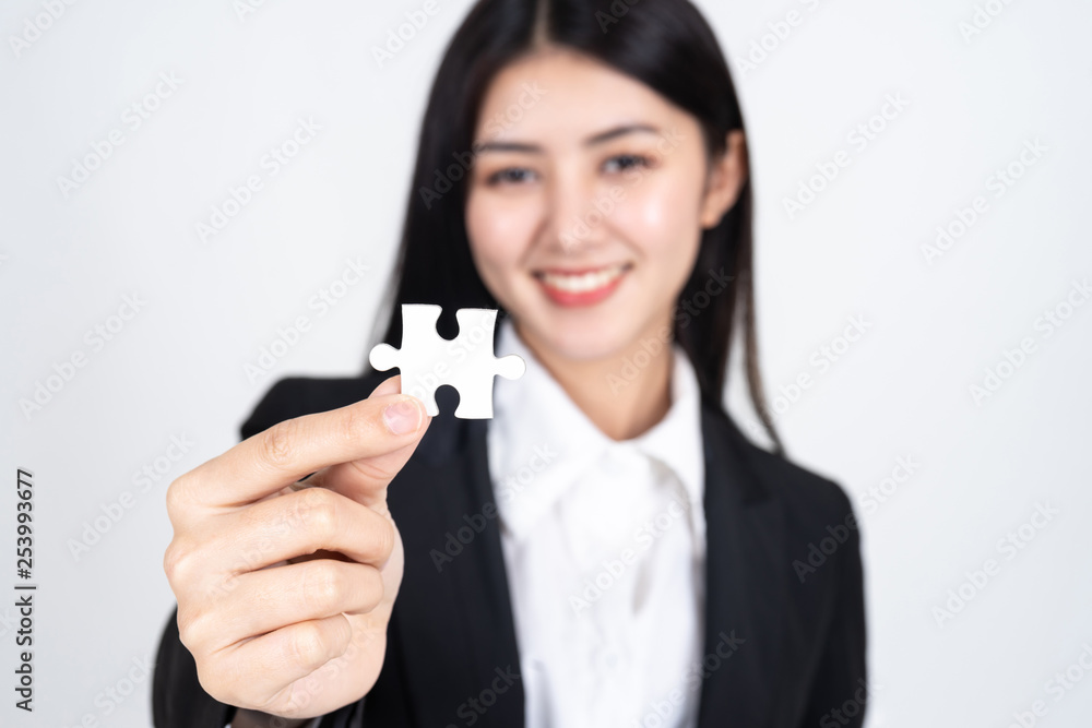 business woman holding and showing a jigsaw puzzle - business concept business woman holding and showing a jigsaw puzzle - business concept