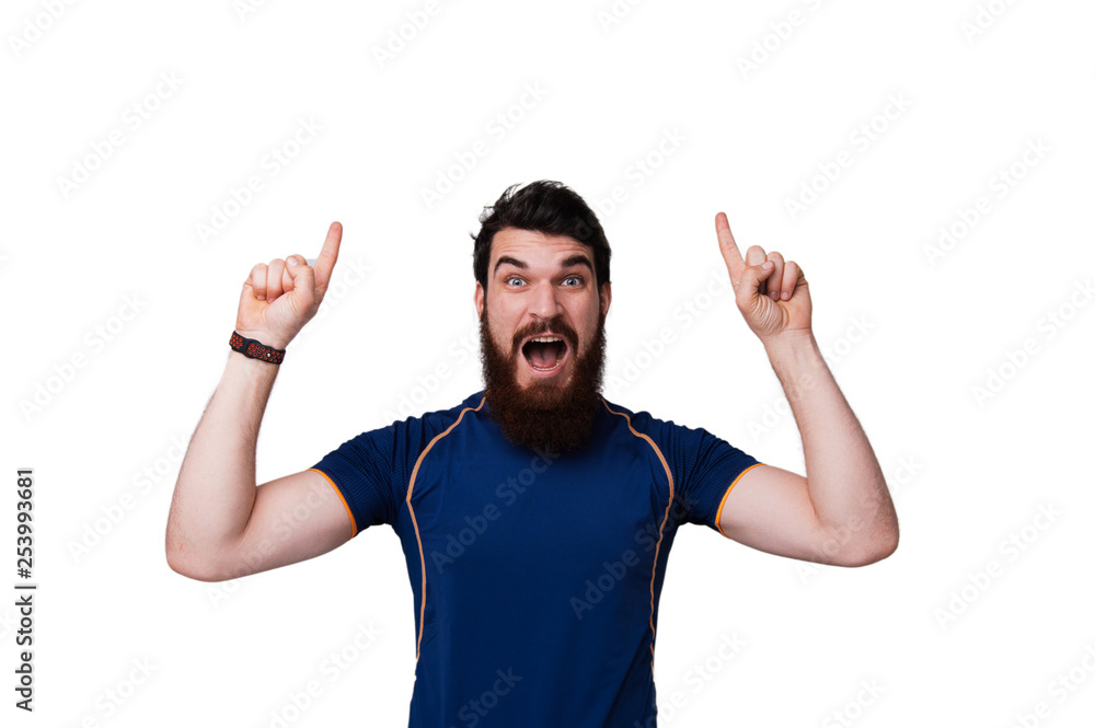Portrait of excited bearded man in checkered shirt pointing fingers up over white background Portrait of excited bearded man in checkered shirt pointing fingers up over white background