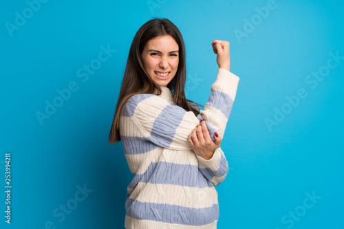 Young woman over blue wall proud and self-satisfied