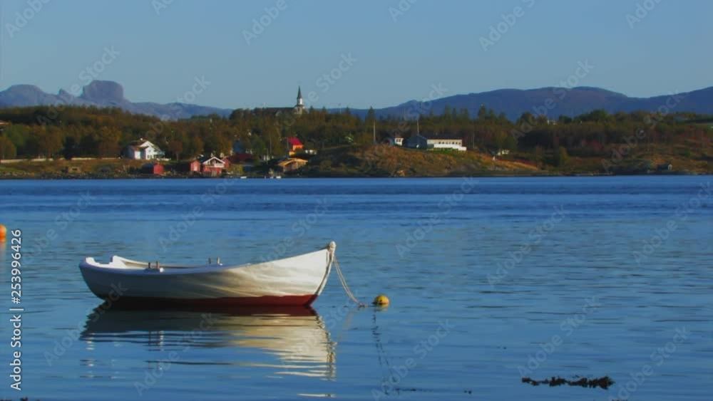 small boat anchored near the coast and the village in the background small boat anchored near the coast and the village in the background