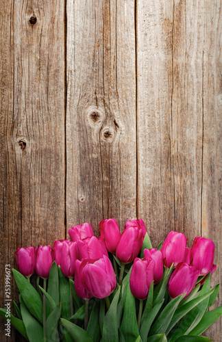 Bouquet of pink tulips on a wooden plank table. Toned photo.