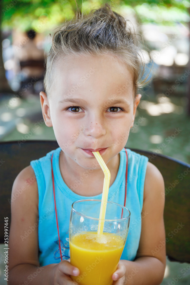 Fototapeta premium beautiful boy is drinking orange juice 