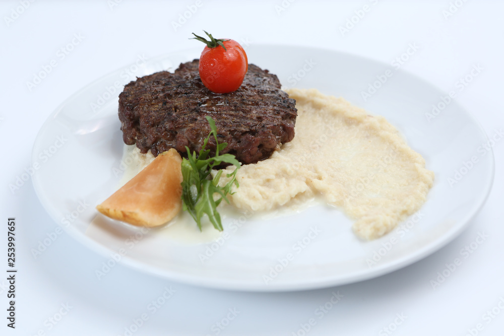 fried meat cutlet on a plate, with celery puree, garnished with tomato cherry and sour apples, isolated fried meat cutlet on a plate, with celery puree, garnished with tomato cherry and sour apples, isolated