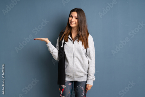 Young sport woman holding copyspace imaginary on the palm to insert an ad