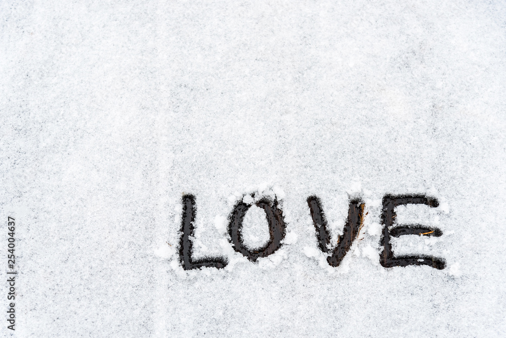 Background of The word love is written in the snow covered wooden area in the winter with copy space. Background of The word love is written in the snow covered wooden area in the winter with copy space.