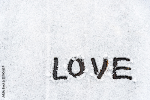 Background of The word love is written in the snow covered wooden area in the winter with copy space.