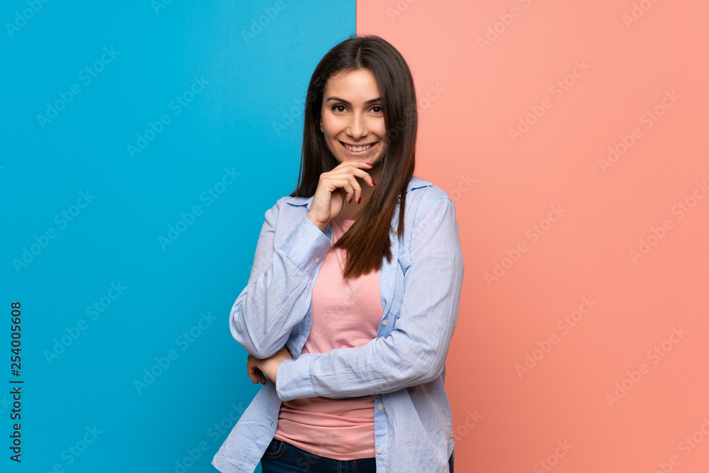 Young woman over pink and blue wall smiling and looking to the front with confident face Young woman over pink and blue wall smiling and looking to the front with confident face