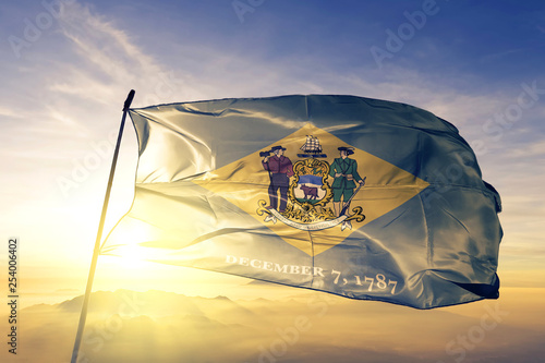 Delaware state of United States flag waving on the top sunrise mist fog photo