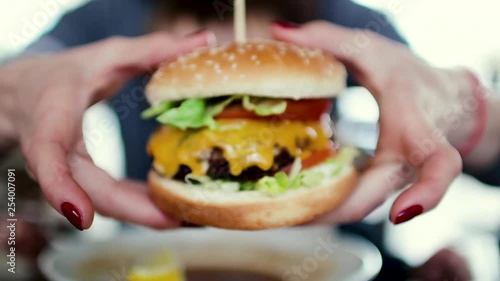 Mum feeds the child a tasty hamburger, cheeseburger