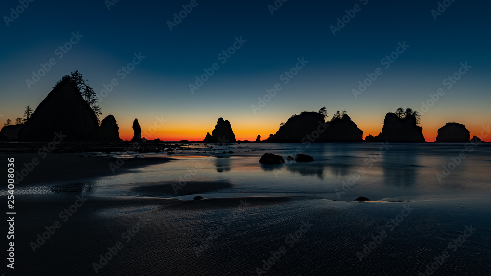 Washington Peninsula's sea stacks backlit by a colorful sunset and clear winter sky