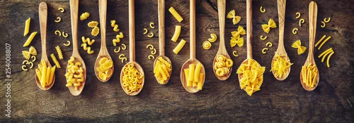 Obraz  z motywem Various kinds of pasta in wooden spoons.