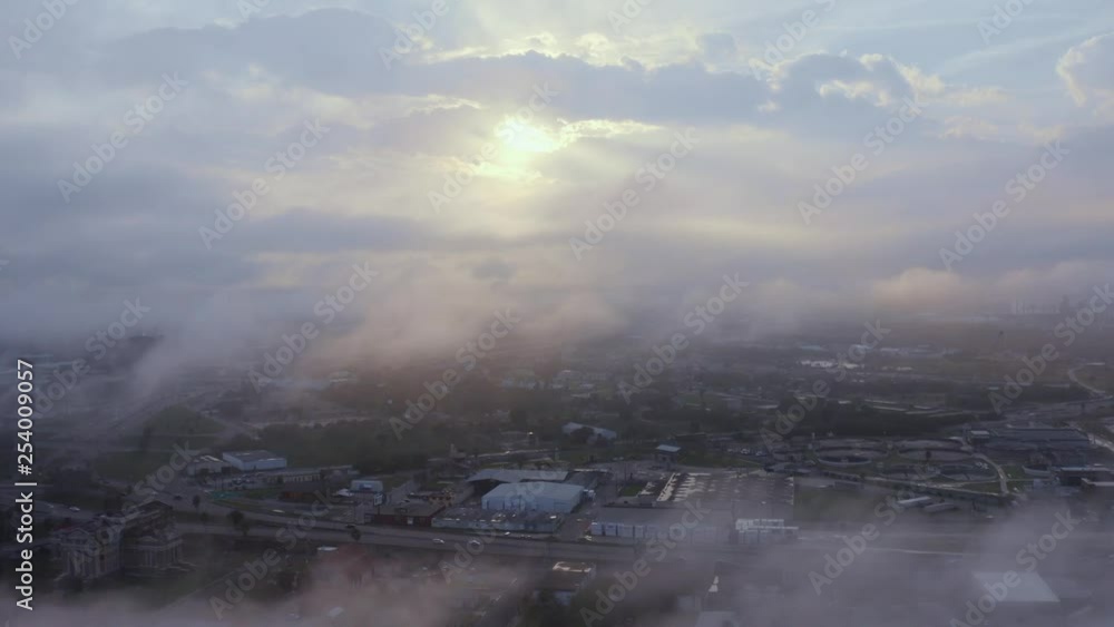 Droning through fog to reveal the sunsetting behind the city. Droning through fog to reveal the sunsetting behind the city.