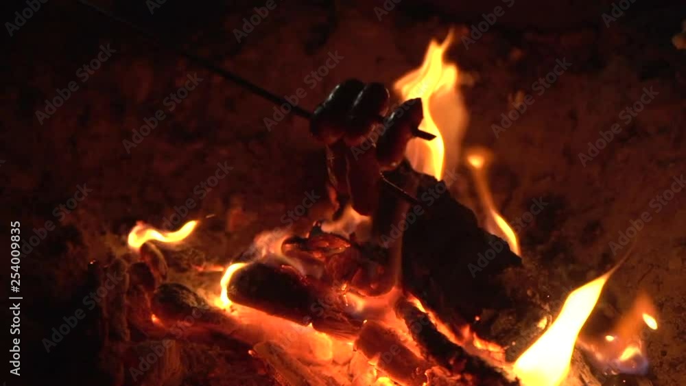 SLOW MOTION: Roasting hot dogs over a nigh campfire SLOW MOTION: Roasting hot dogs over a nigh campfire