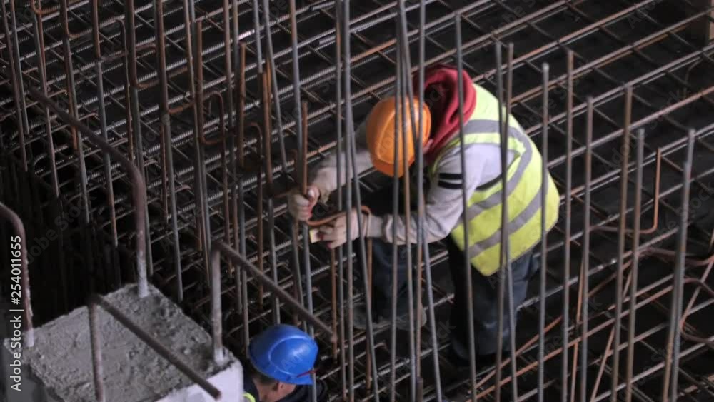 Construction workers install & bend rebar for formwork reinforcement on