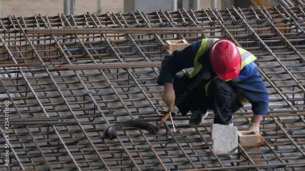 A construction worker uses tools to install rebar on a industrial construction site A construction worker uses tools to install rebar on a industrial construction site