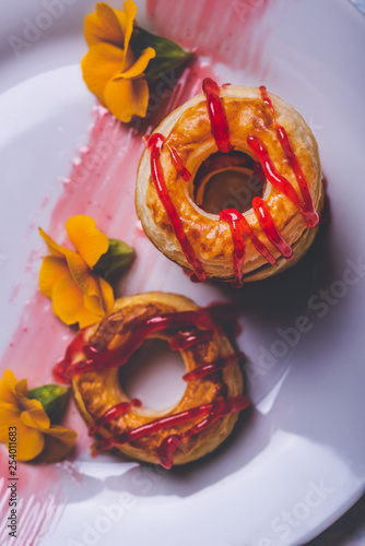 Few puff pastry donuts with strawberry topping on white plate