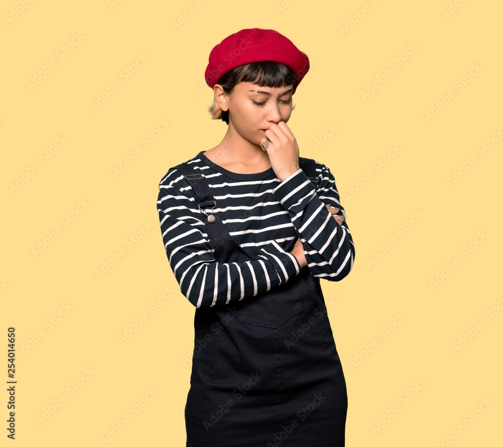 Young woman with beret having doubts over yellow background Young woman with beret having doubts over yellow background