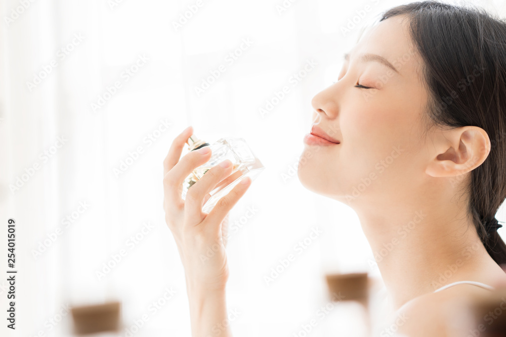 Asian girl with perfume, young woman applying perfume on her wrist and smelling Asian girl with perfume, young woman applying perfume on her wrist and smelling