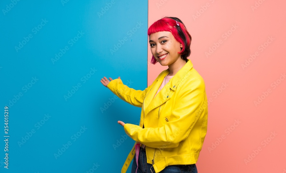 Young woman with yellow jacket pointing back and presenting a product