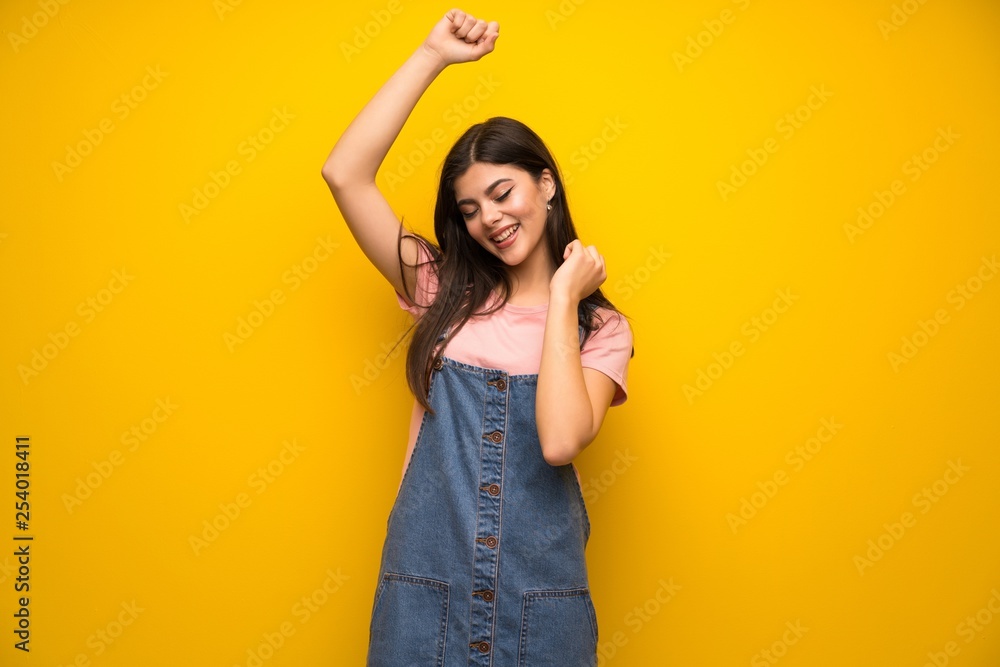 Teenager girl over yellow wall celebrating a victory Teenager girl over yellow wall celebrating a victory