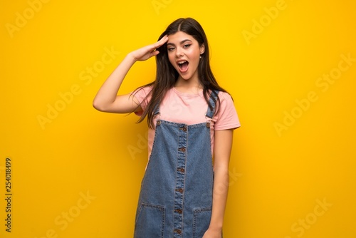 Teenager girl over yellow wall has just realized something and has intending the solution