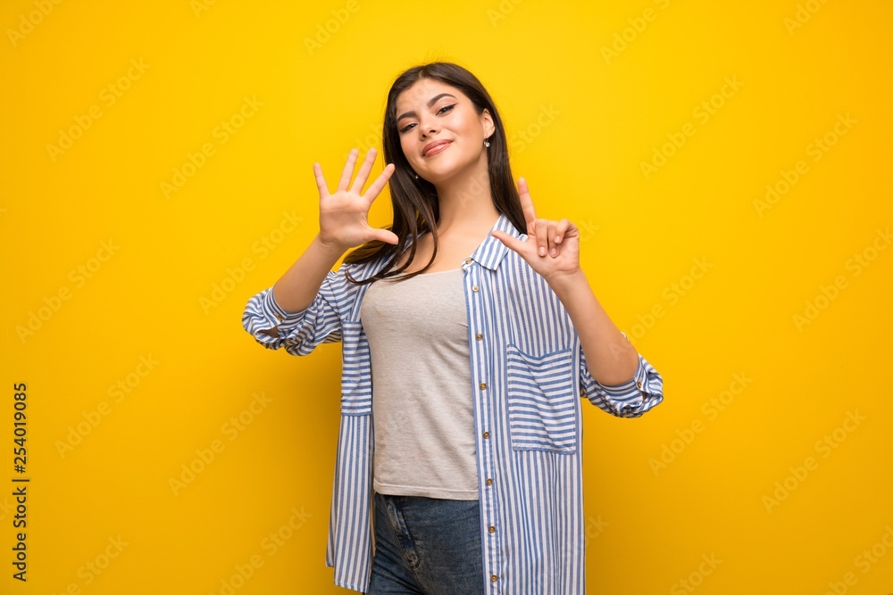 Teenager girl over yellow wall counting seven with fingers Teenager girl over yellow wall counting seven with fingers