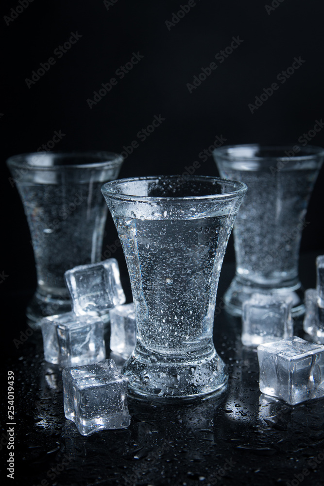 Russian vodka shot with ice on black background Russian vodka shot with ice on black background