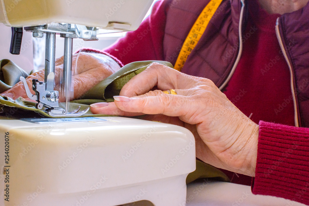 Senior streamstress sewing with an old sewing machine