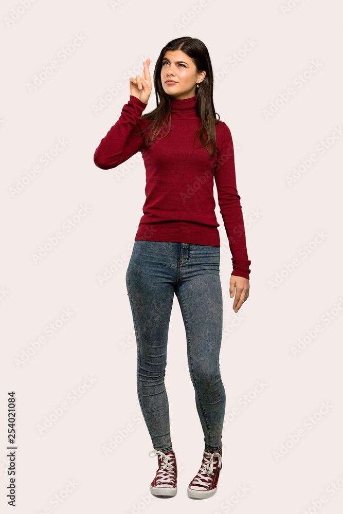 A full-length shot of a Teenager girl with turtleneck with fingers crossing and wishing the best over isolated background A full-length shot of a Teenager girl with turtleneck with fingers crossing and wishing the best over isolated background