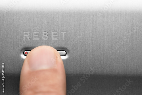 The reset button on the aluminum panel. Male finger. photo