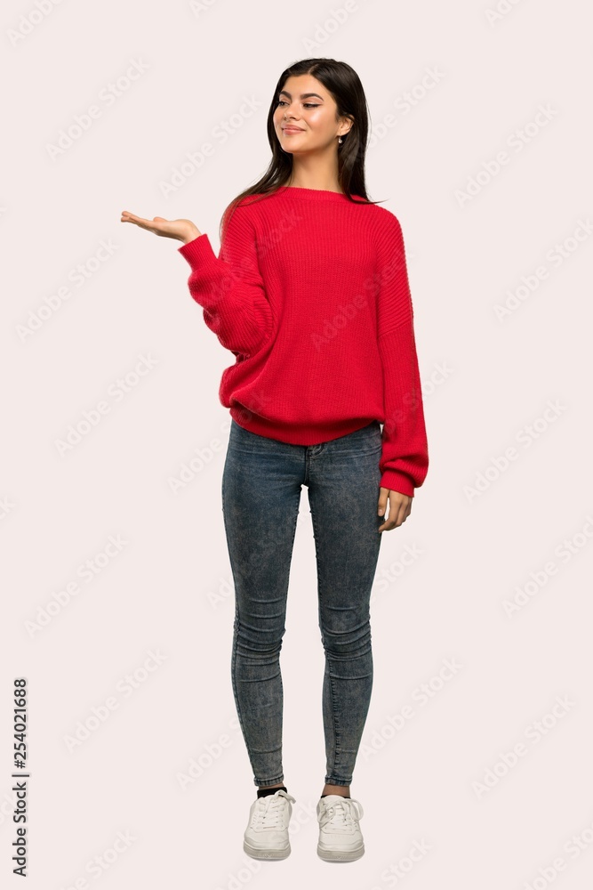 A full-length shot of a Teenager girl with red sweater holding copyspace imaginary on the palm to insert an ad over isolated background A full-length shot of a Teenager girl with red sweater holding copyspace imaginary on the palm to insert an ad over isolated background