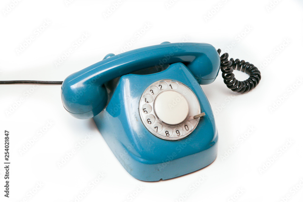 A blue old retro rotary mechanical phone isolated on a white background. A blue old retro rotary mechanical phone isolated on a white background.