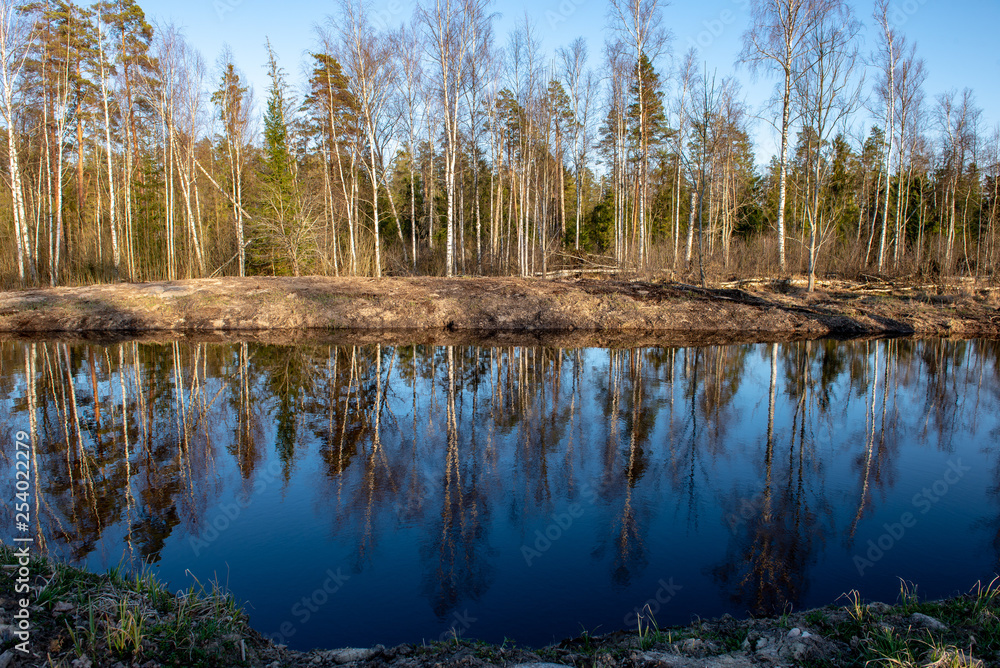 riverside landscape in latvia with dark water and dirty shore line riverside landscape in latvia with dark water and dirty shore line