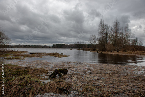 riverside landscape in latvia with dark water and dirty shore line