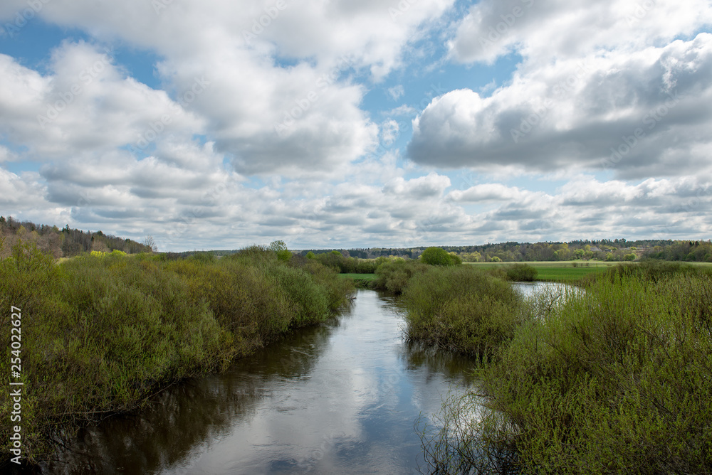 riverside landscape in latvia with dark water and dirty shore line