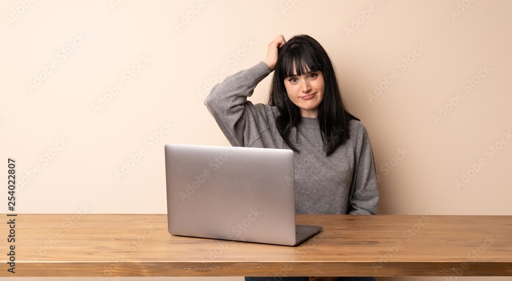 Young woman working with her laptop with an expression of frustration and not understanding